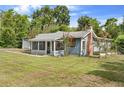 Angle view of a single-story home with screened in front porch, brick chimney, and detached garage at 710 W May St, Deland, FL 32720