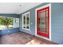 Covered front porch featuring a red front door and red brick flooring adding a pop of color to the home at 710 W May St, Deland, FL 32720