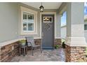 Inviting front porch with stone accents, a comfortable chair, and decorative floral arrangements at 7732 Sw 86Th Ct, Ocala, FL 34481