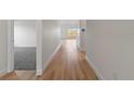 Hallway with light wood flooring leading to a carpeted room with white walls at 822 W 24Th St, Sanford, FL 32771