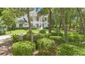 Manicured landscaping surrounds a two-story home with columns, visible through trees at 1155 Taylor E Rd, Deland, FL 32724