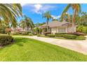 Charming home with a circular driveway, lush landscaping, and mature palm trees at 15 Cambridge Trce, Ormond Beach, FL 32174