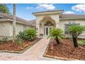 Inviting entryway featuring arched doorway and lush tropical landscaping at 19 Tomoka Cove Way, Ormond Beach, FL 32174