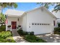 Beautiful white home showcasing an attached two car garage, well maintained landscaping, and a cozy red door at 232 River Village Dr, Debary, FL 32713