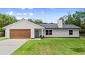Charming single-story home featuring a new roof, an attached garage, fresh paint, and a bright green front door at 2455 Whooping Crane Dr, De Leon Springs, FL 32130