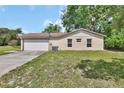 Side view of home featuring a two-car garage and well-kept lawn at 28045 Poinsettia Ave, Paisley, FL 32767