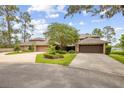 A well-maintained property with lush landscaping and a large driveway leading to multiple garages at 510 Sandy Bluff Trl, Deland, FL 32724
