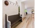 Stylish entryway features planked walls, coat hooks, a charming bench, and beautiful wood flooring at 565 Morgan Wood Dr, Deland, FL 32724
