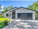 Charming home featuring a two-car garage with modern doors, situated on a lush, green lot at 28432 Tammi Dr, Tavares, FL 32778
