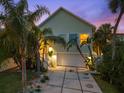 Charming home exterior with a two-car garage, tropical landscaping, and a well-lit front porch at 3110 John Anderson Dr, Ormond Beach, FL 32176