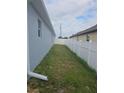 Narrow side yard with grass and a white vinyl fence provides privacy at 3339 Croton Ave, Deltona, FL 32738