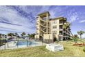Exterior view featuring pool, stairs, and palm trees surrounding a condo building on a sunny day at 2390 Ocean Shore Blvd # 1040, Ormond Beach, FL 32176
