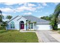 Light blue one-story house with a red door and attached garage at 12450 Greco Dr, Orlando, FL 32824