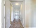 Neutral hallway featuring sleek tile flooring and light-colored walls, leading to bright rooms at 2588 Egret Loop, Kissimmee, FL 34743