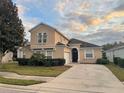 Two-story house with tan siding, landscaping, and a paved driveway at 629 Copeland Dr, Haines City, FL 33844