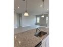 Kitchen island with granite countertops and stainless steel sink overlooking living room at 380 Crossings Ave, St Cloud, FL 34771