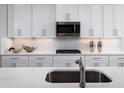 Kitchen detail showcasing white cabinets, stainless steel appliances, quartz countertops, and herringbone backsplash at 1632 Covey Rise Ter, Winter Haven, FL 33884