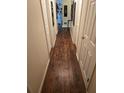 A hallway featuring wood-look floors and neutral walls, adorned with framed artwork at 600 Se 52Nd Ave, Ocala, FL 34471