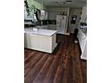 Cozy kitchen with white cabinets, an island with granite counters and dark hardwood floors at 600 Se 52Nd Ave, Ocala, FL 34471