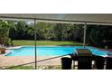Outdoor pool area with a barbecue grill and surrounded by lush greenery offering a private backyard at 600 Se 52Nd Ave, Ocala, FL 34471
