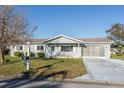 Charming single-story home with a well-manicured lawn, screened-in garage, and beautiful landscaping at 17975 Se 106Th Ct, Summerfield, FL 34491