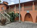 Condominium building with orange walls, stairs to the units, and tropical foliage at 722 E Michigan St # 145, Orlando, FL 32806