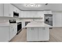 Bright kitchen boasts white cabinets, stainless steel appliances, large island and modern finishes at 20995 Sw 93Rd Lane Rd, Dunnellon, FL 34431