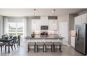 Bright kitchen with white cabinets, granite countertops, stainless steel appliances, island seating, and dining area at 1916 Quail Fields Cir, Winter Haven, FL 33884