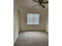 This cozy carpeted bedroom is filled with light from a window and features a ceiling fan at 4931 Tropicana Dr, Indian Lake Estates, FL 33855