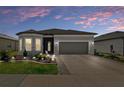 Charming one-story home featuring stone accents, manicured landscaping, and a gray two-car garage at dusk at 8534 Sw 59Th Lane Rd, Ocala, FL 34481