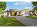Beautiful home featuring a gray exterior, a well-manicured lawn, a brick driveway, and mature trees at 248 Lake Tennessee Dr, Auburndale, FL 33823