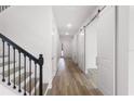 Bright hallway with wood floors, staircase, and modern barn doors creating an inviting entryway at 9432 Emerald Berry Dr, Winter Garden, FL 34787