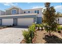 Charming townhome featuring a brick driveway, two-car garage, and manicured landscaping at 5228 Luisa Ct, St Cloud, FL 34771