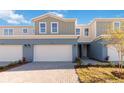 Charming townhome featuring a two-car garage, a light blue painted exterior, and manicured landscaping at 5289 Luisa Ct, St Cloud, FL 34771