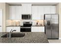 Modern kitchen featuring stainless steel appliances, granite counters, and white cabinets at 5000 Balsam Falls Rd, Deland, FL 32724