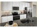 Modern kitchen featuring white cabinetry, granite countertops, stainless steel appliances, and stylish backsplash at 5056 Bear Lake Loop, Deland, FL 32724