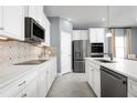 Gourmet kitchen features white cabinetry, stainless steel appliances, and stylish backsplash design at 5031 Bear Lake Loop, Deland, FL 32724