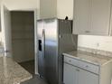 Open pantry next to stainless steel refrigerator, gray cabinets, and granite countertop at 1707 Jindo Dr, Lake Alfred, FL 33850