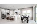 Modern kitchen featuring white cabinetry, stainless steel appliances, a center island with seating, and an adjacent dining area at 11030 Nellie Crossing Cir, Clermont, FL 34711