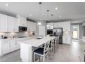 Modern kitchen boasts white cabinetry, stainless steel appliances, a spacious island, and pendant lighting for a contemporary feel at 11054 Nellie Crossing Cir, Clermont, FL 34711