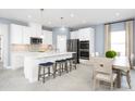 Modern kitchen featuring white cabinetry, stainless steel appliances, a center island with seating, and pendant lighting at 1310 Whispering Ln, Minneola, FL 34715
