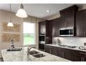 Contemporary kitchen with stainless steel appliances, granite countertops, and dark wood cabinets at 3758 Voyageurs Ct, Apopka, FL 32712