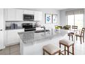 Bright kitchen features white cabinets, stainless steel appliances, granite counters, and a breakfast bar with seating at 1381 Laramie Way, Haines City, FL 33844