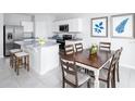 Inviting kitchen flows to dining area with white cabinets, granite counters, island seating, and stainless appliances at 1531 Landon Ln, Haines City, FL 33844