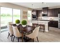 Open kitchen and dining area with wood floors, dark cabinets, granite countertops, and large windows at 3190 Tiger Palm Way, New Smyrna Beach, FL 32168
