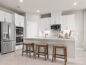 Bright kitchen with white cabinets, stainless steel appliances, a tile backsplash, and breakfast bar seating at 1278 Whispering Ln, Minneola, FL 34715