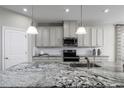 Close-up of granite kitchen island with black and white accents; pendant lights and stainless steel appliances at 11037 Nellie Crossing Cir, Clermont, FL 34711