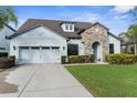 Beautiful home showcasing a blend of stone and light blue siding, a two-car garage, and a neatly kept front lawn at 1382 Heritage Landings Dr, Lakeland, FL 33805