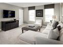 Comfortable living room with a plush white sectional sofa, modern ottoman, and a sleek entertainment center with a large television at 1327 Whispering Ln, Minneola, FL 34715