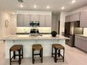 Modern kitchen boasts stainless steel appliances, granite countertops, gray cabinets, and a stylish center island with barstool seating at 5240 Luisa Ct, St Cloud, FL 34771